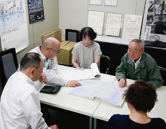 図面を囲んで打ち合わせをする社員たち